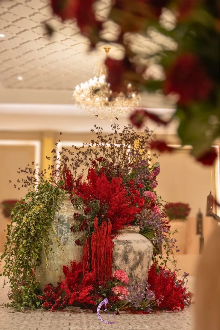 Lush red floral arrangement displayed in textured stone urns