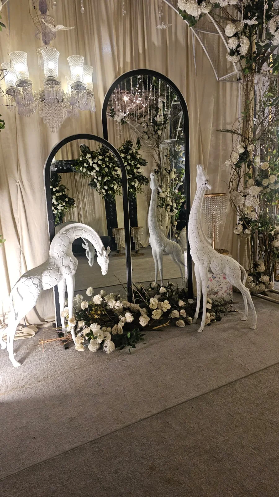White sculptural giraffe installation with mirrors and florals